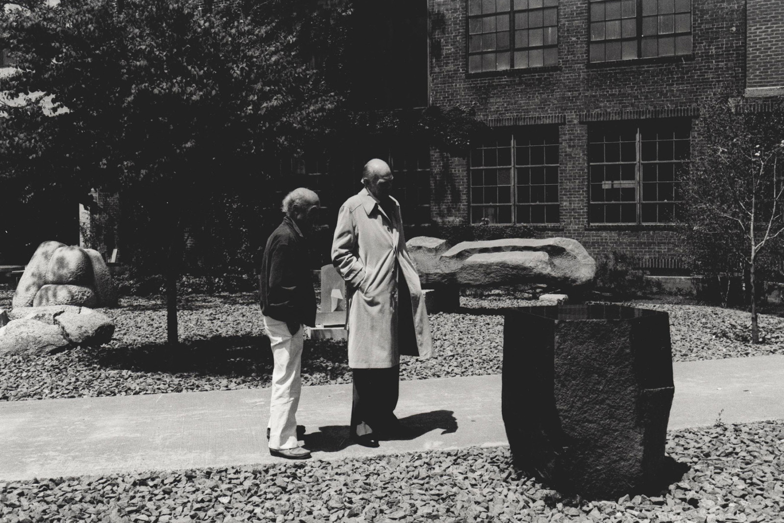Photograph by Shigeo Anzai of Isamu Noguchi showing a guest around the Museum garden in 1985