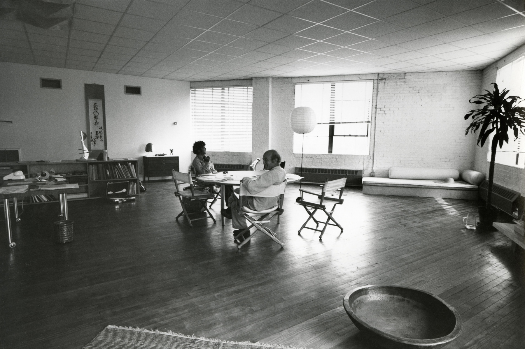 Isamu Noguchi and Ikeda Masuo sit around a table in the 3237 Vernon Boulevard warehouse in 1977