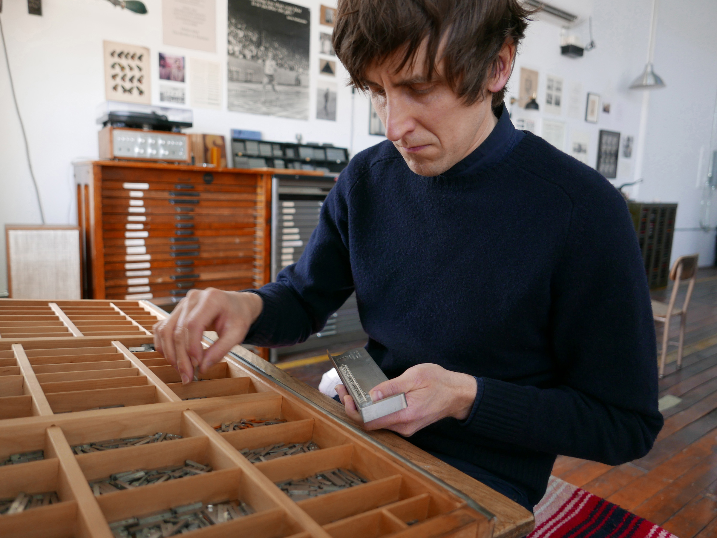 Jon Beacham of The Brother In Elysium setting metal letterpress type with a composing stick in...